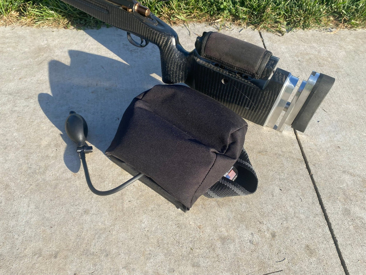 Black RyanCheneyELR Endgame rear bag with side-mounted hand pump and webbing handle, shown beneath a rifle stock in a manufacturer photograph.